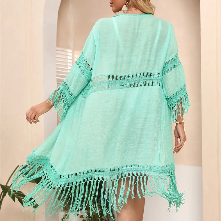Yellow hand-crocheted beach cardigan with tassel stitching on a hanger.