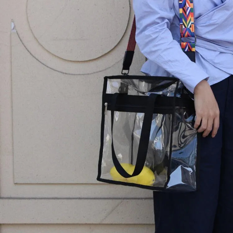 Women's transparent PVC shoulder messenger bag showing front organisation and double strap connector
