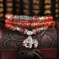 Close-up of a handmade watermelon crystal bracelet with a central Chinese knot and geometric beads.
