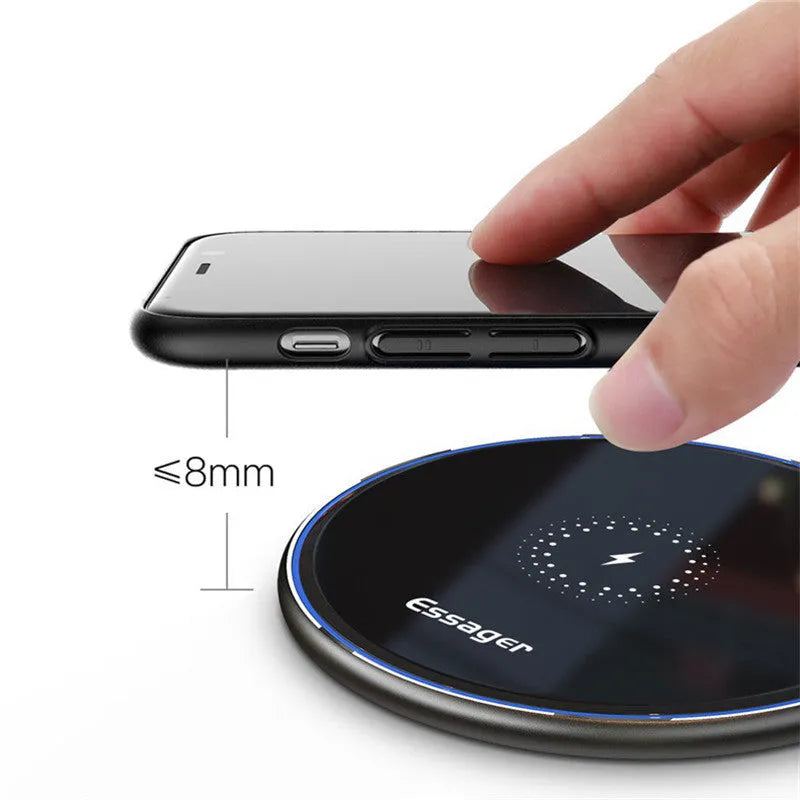 Black 15W Qi wireless charging pad on a wooden surface showing blue LED charging light