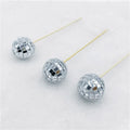 Glass mirror disco ball cake decoration on a wooden stick, showing reflective surface.