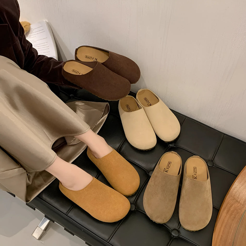 Flat apricot coloured slip-on slippers with a square toe and microfiber upper on a light surface.
