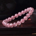 Close-up of a women's bracelet with polished strawberry quartz crystal beads in natural tones.
