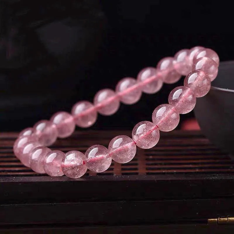 Close-up of a women's bracelet with polished strawberry quartz crystal beads in natural tones.