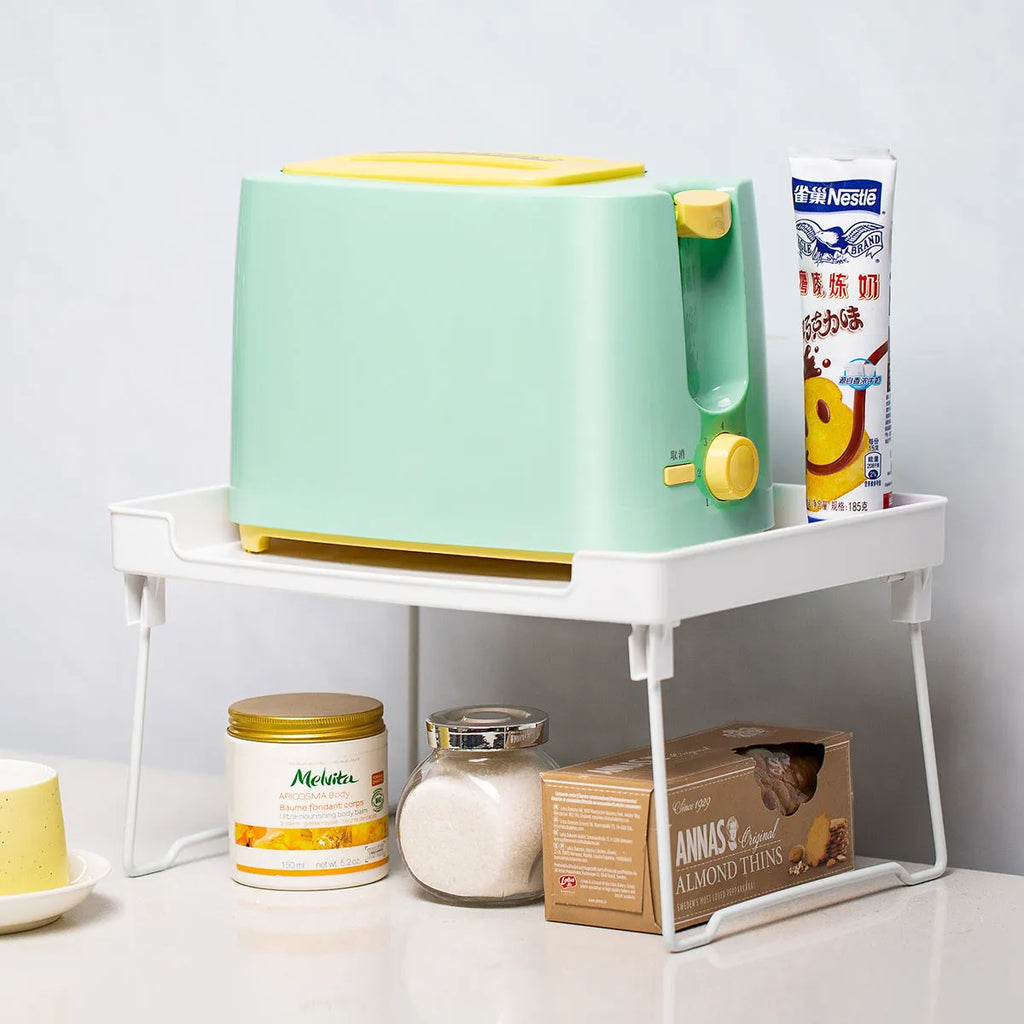 Transparent plastic kitchen supplies rack on a white countertop holding small items