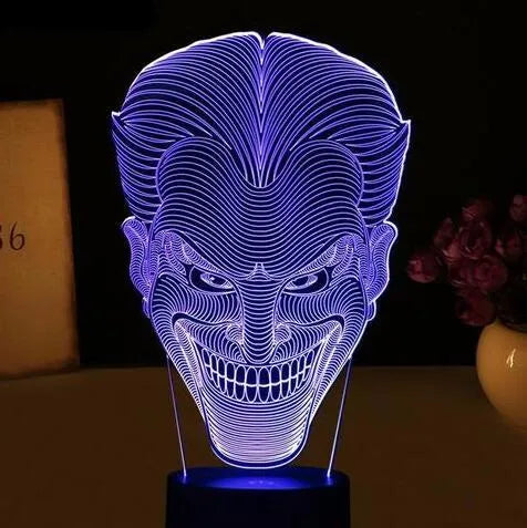 A 3D acrylic LED table lamp with a remote control on a desk, showing its colourful gradient light mode.