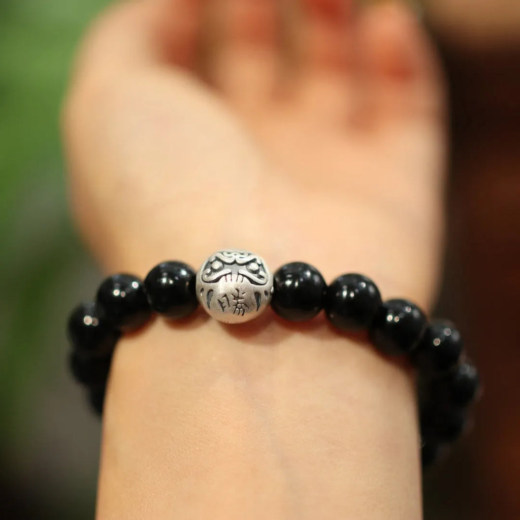 Close-up of a bracelet with large round black agate beads and sterling silver components on a wrist.