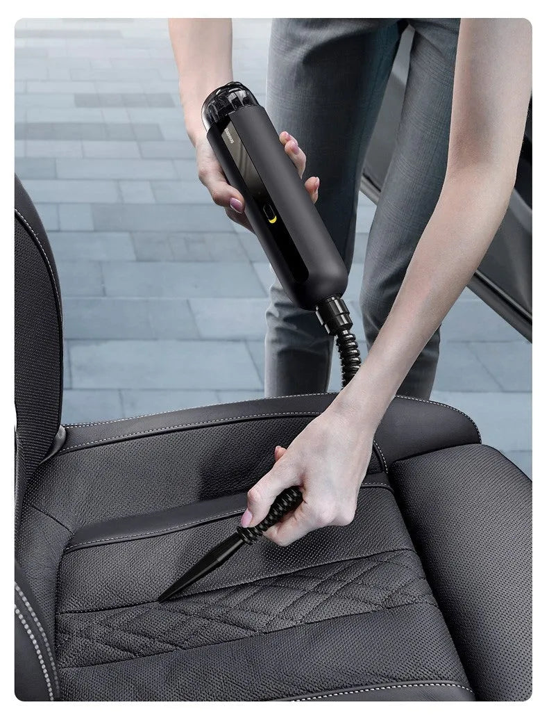 BASEUS wireless handheld car vacuum cleaner in black on a car seat, showing compact size and nozzle attachment.