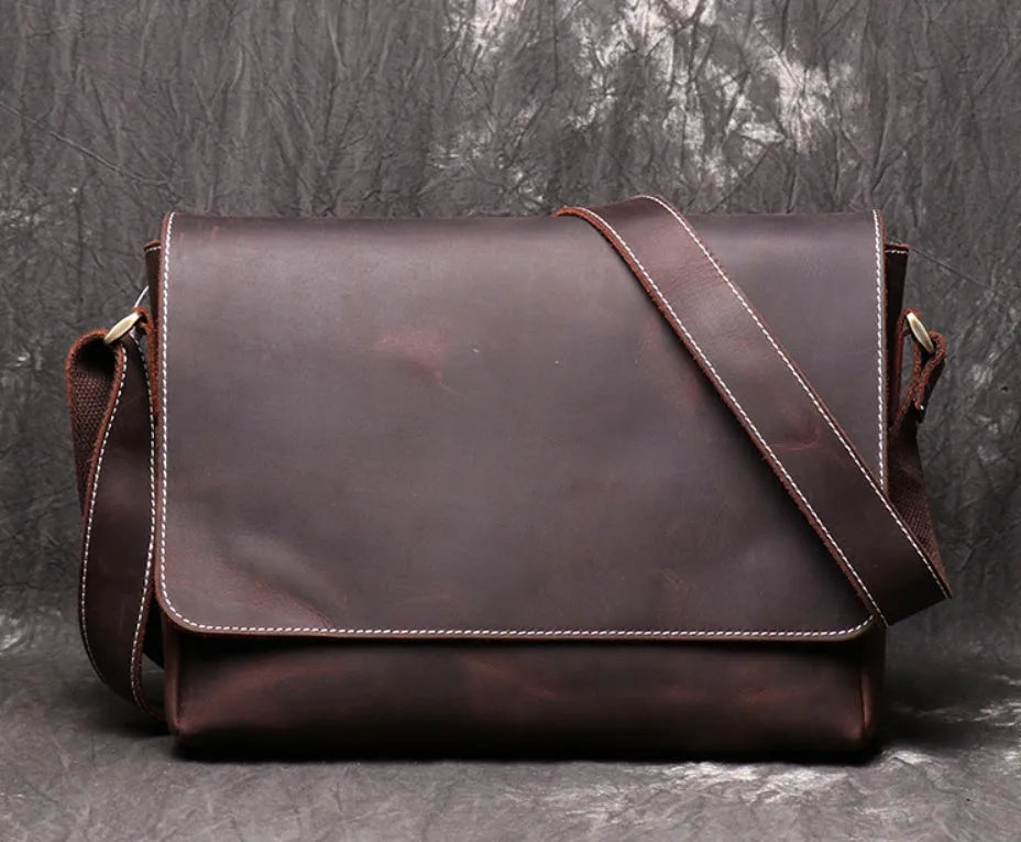 Vintage brown leather mens messenger bag with a shoulder strap, shown open to reveal internal organiser pockets.