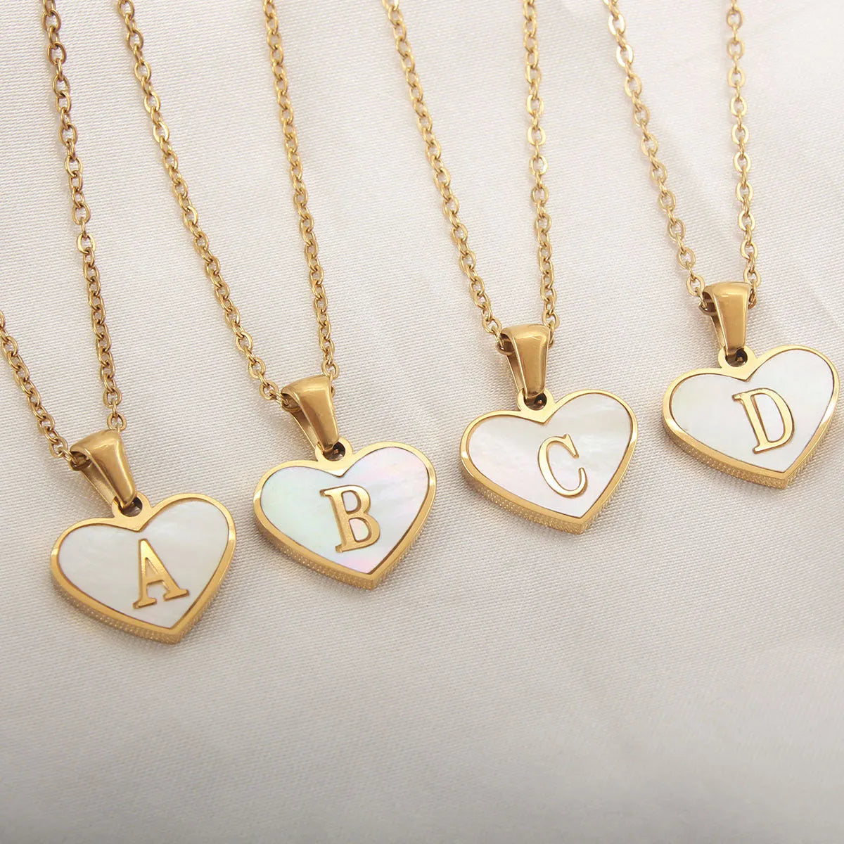 Gold heart-shaped white shell necklace with personalised letter charm on adjustable chain