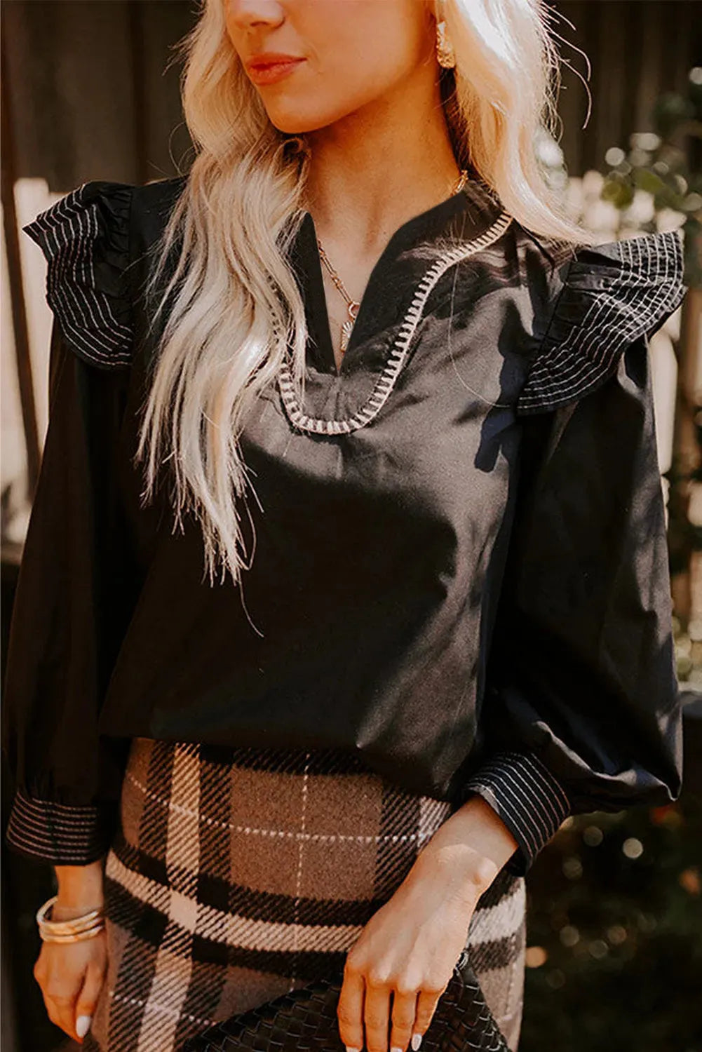 Black women's long sleeve blouse with v-neck ruffle detail and white contrast stitching