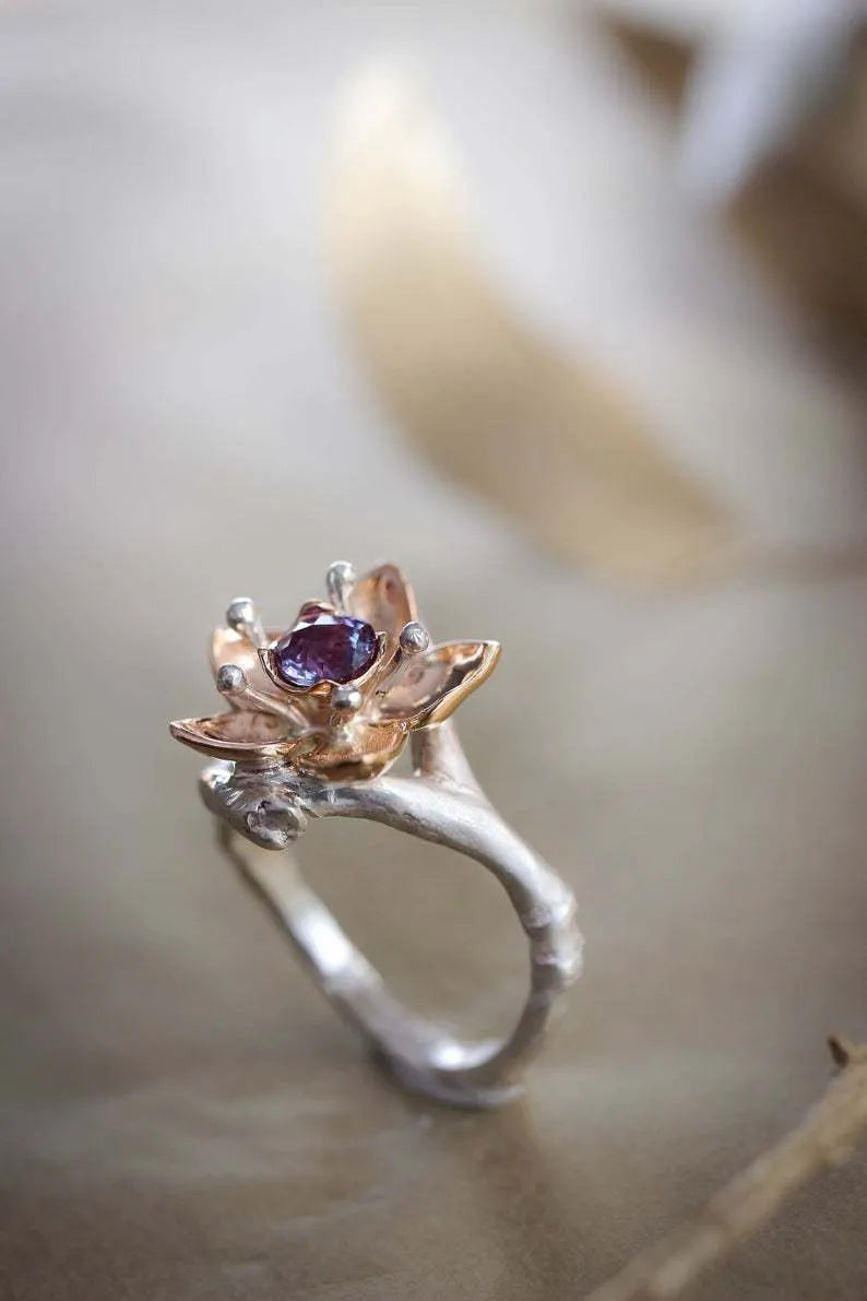 Silver two-tone women's ring with a geometric shape and floral design on a grey background