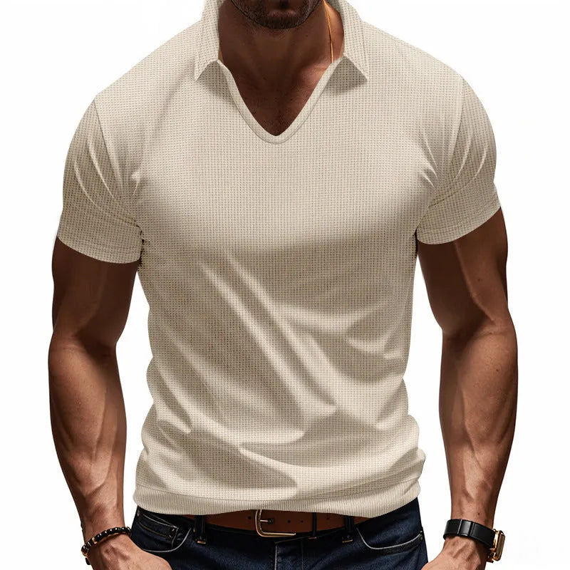 Man wearing a loose-fitting apricot V-neck short sleeve t-shirt against a plain background.