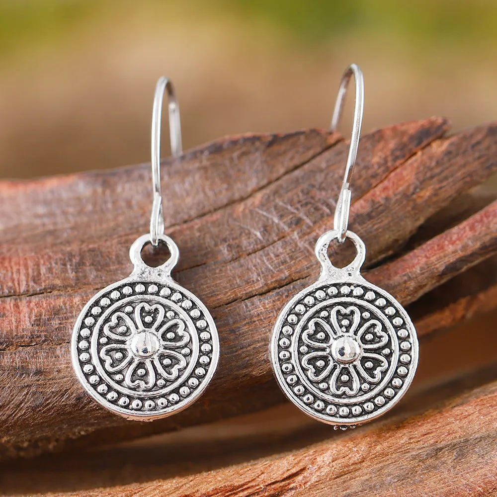 Close-up of a pair of women's geometric round bohemian retro style earrings with a distressed ethnic design in zinc alloy.