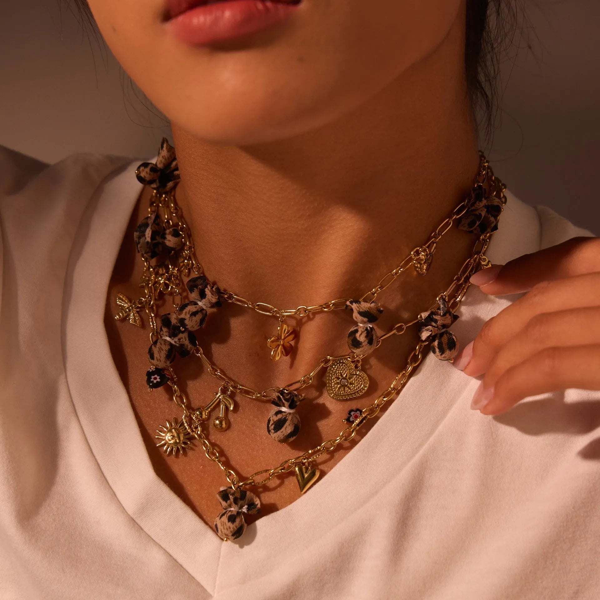 Stainless steel necklace with geometric pendant showing leopard spots, love hearts and flowers in gold finish