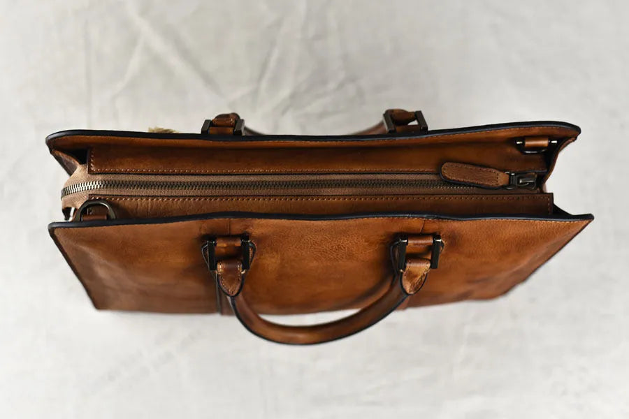 Men's brown leather retro handbag with horizontal square shape and zipper opening.
