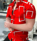Man wearing a slim fit short sleeve shirt with a colourful 3D floral print, on a beach.