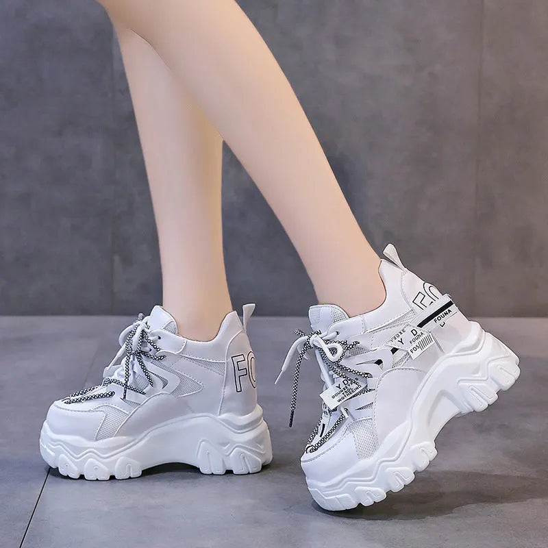 White and black women's low-top platform sports shoes with cross-strap and mesh design on a rubber sole.
