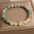 Natural crystal bracelet for women oil green emerald colour with sutra carvings on a white background