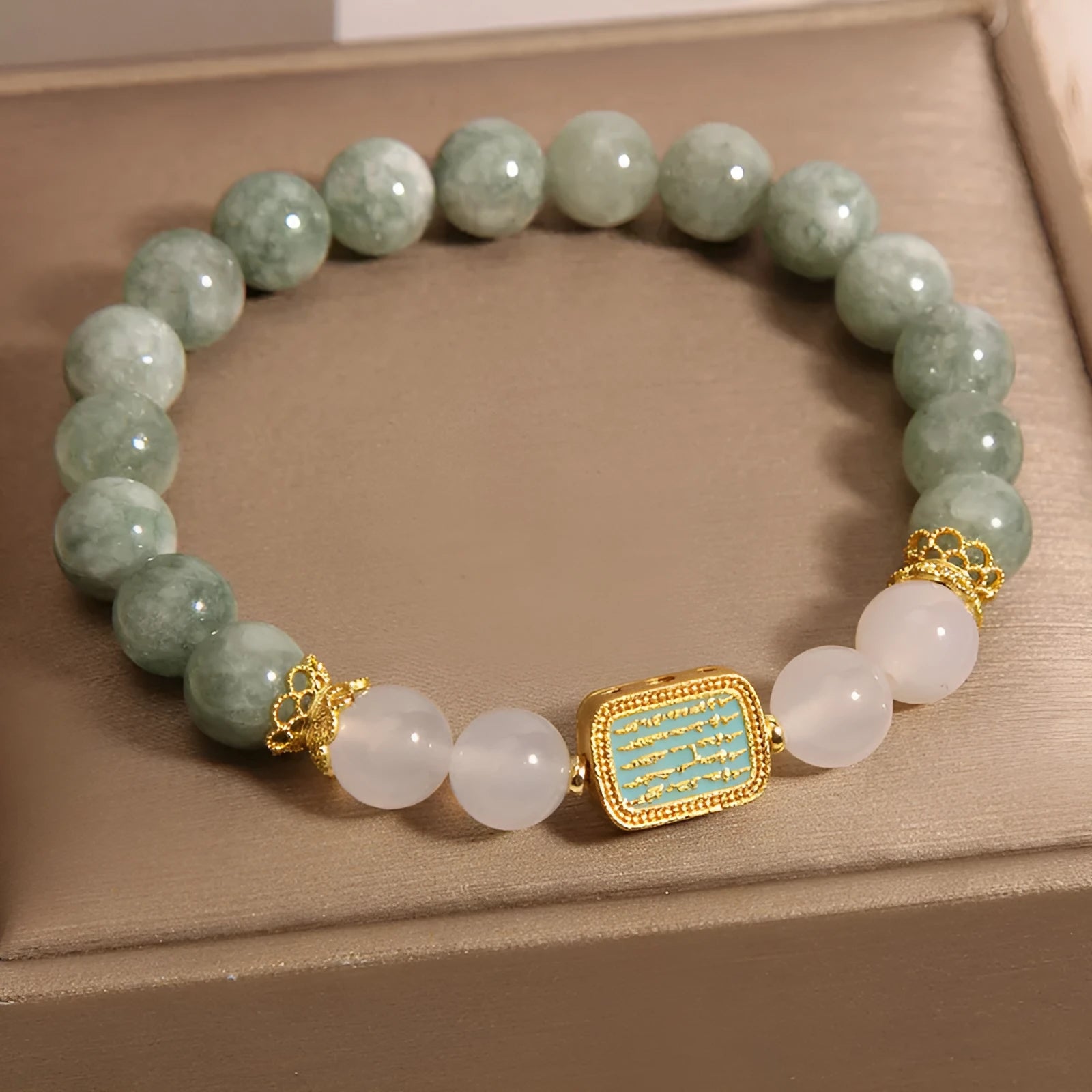 Natural crystal bracelet for women oil green emerald colour with sutra carvings on a white background