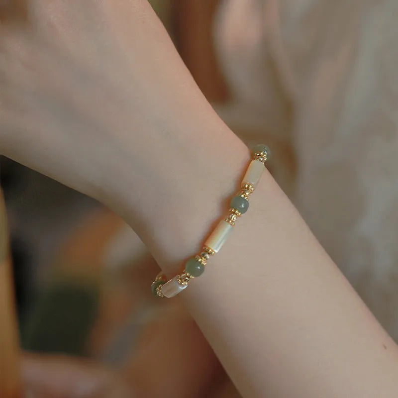 Natural Hetian jade and white lip shell round bead bracelet on neutral background, single bead option