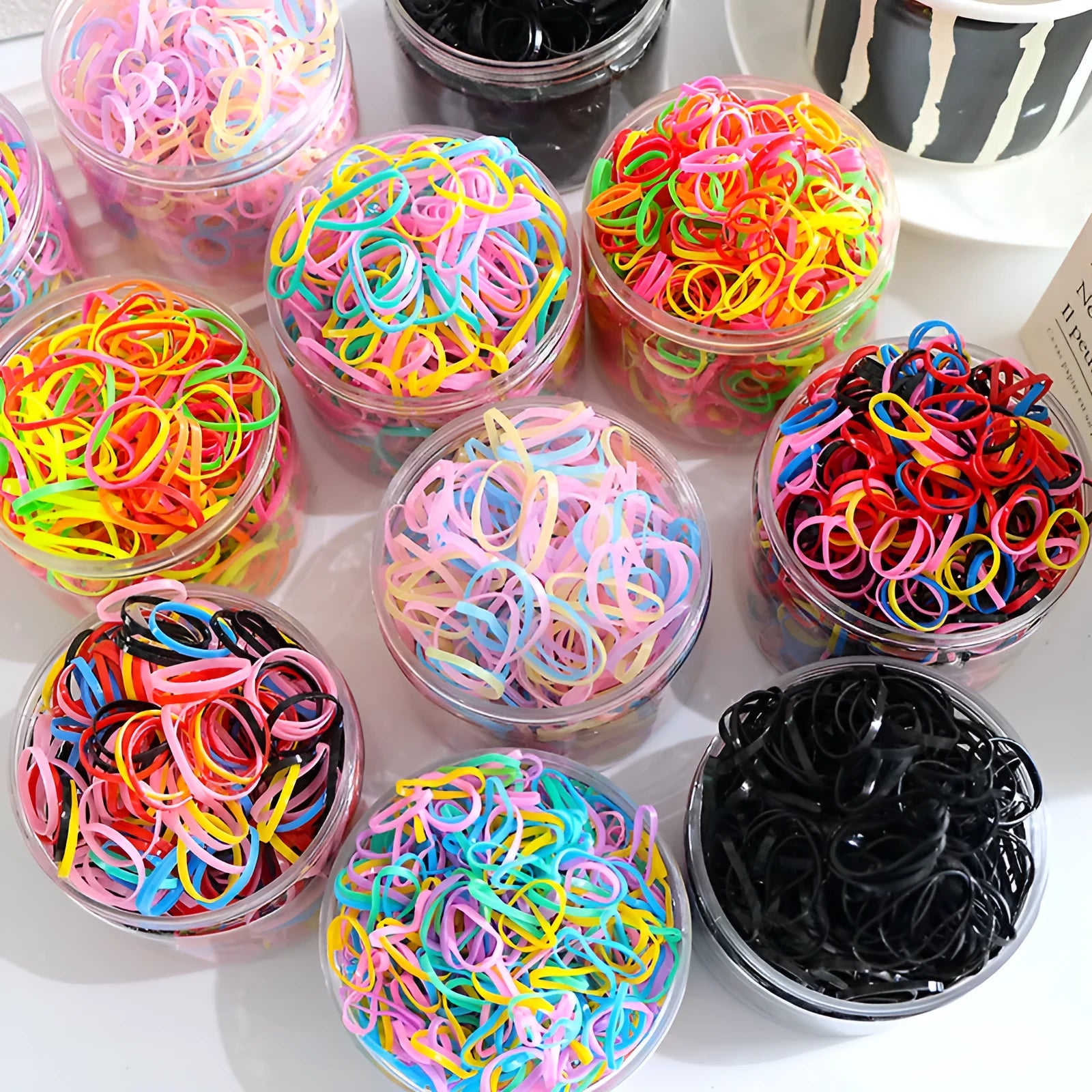 300 or 600 piece pack of baby hair ties in assorted colours, small TPU elastic bands for fine hair, supplied in a reusable container