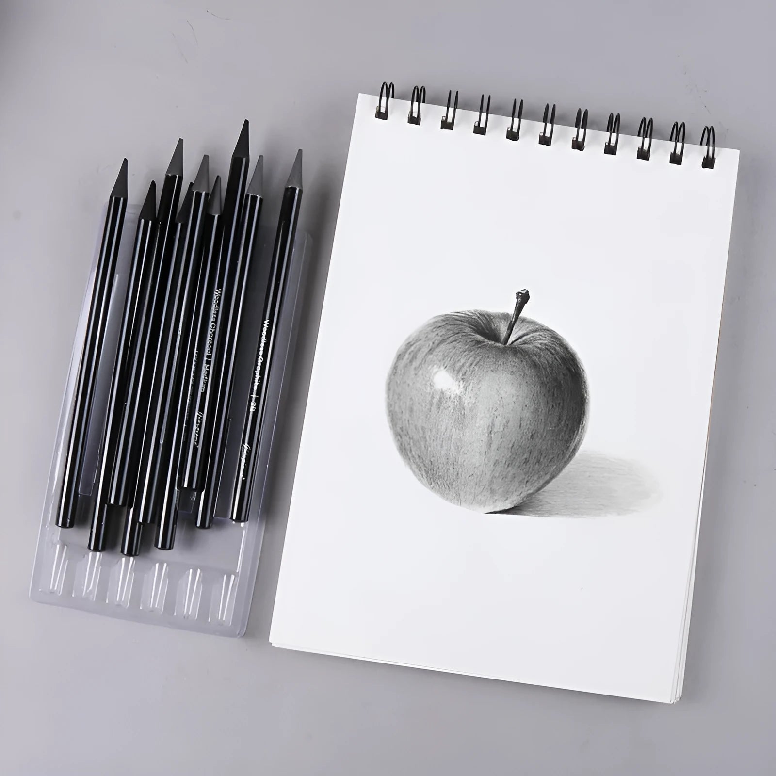 Set of six graphite pencils and three carbonized pencils in wooden casings on suction card packaging.