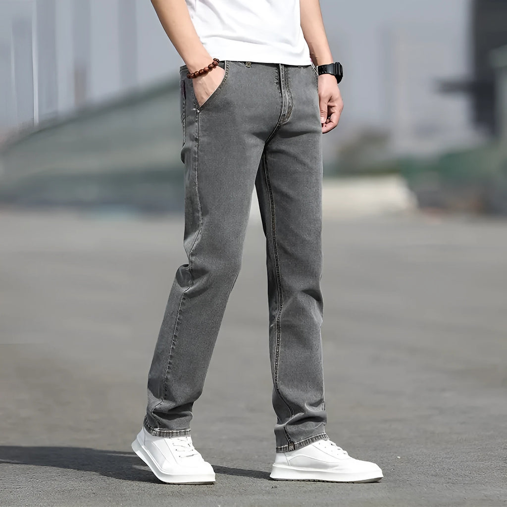 Men's smoky grey low waist straight leg jeans with a zipper fly, shown on a hanger.