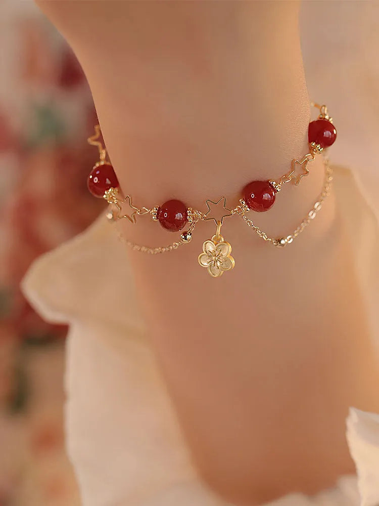 Red agate double layer bracelet with peach blossom charm on an adjustable elastic cord.
