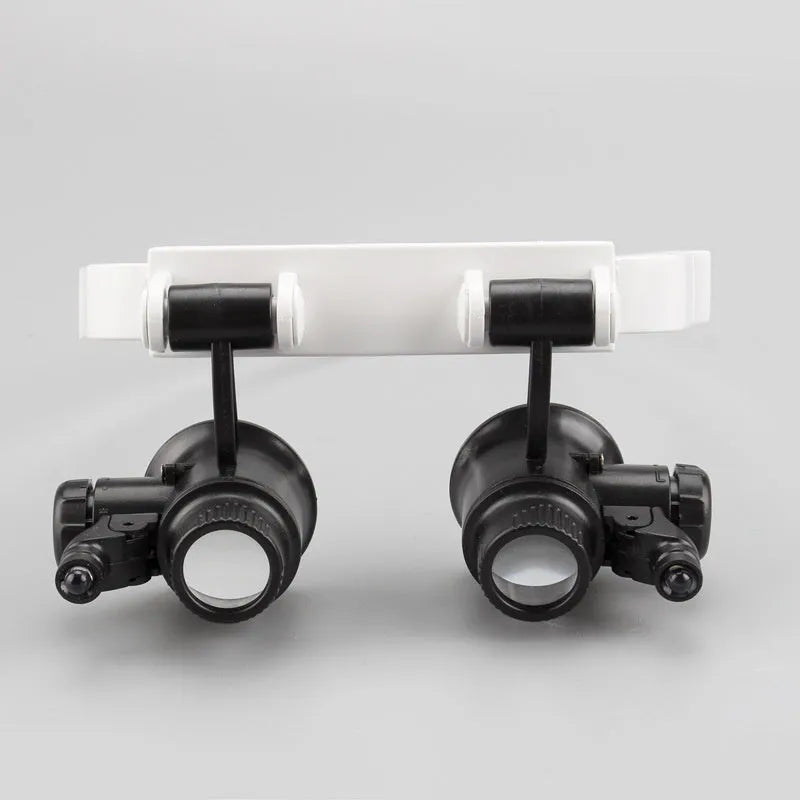 White head mounted magnifying glass with LED light, 30x optical glass lenses, folded to show compact storage size