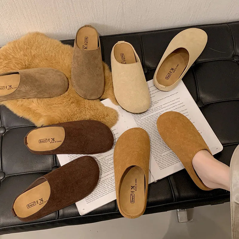Flat apricot coloured slip-on slippers with a square toe and microfiber upper on a light surface.