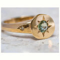 Gold coloured oval star zircon ring with adjustable opening on a plain background.