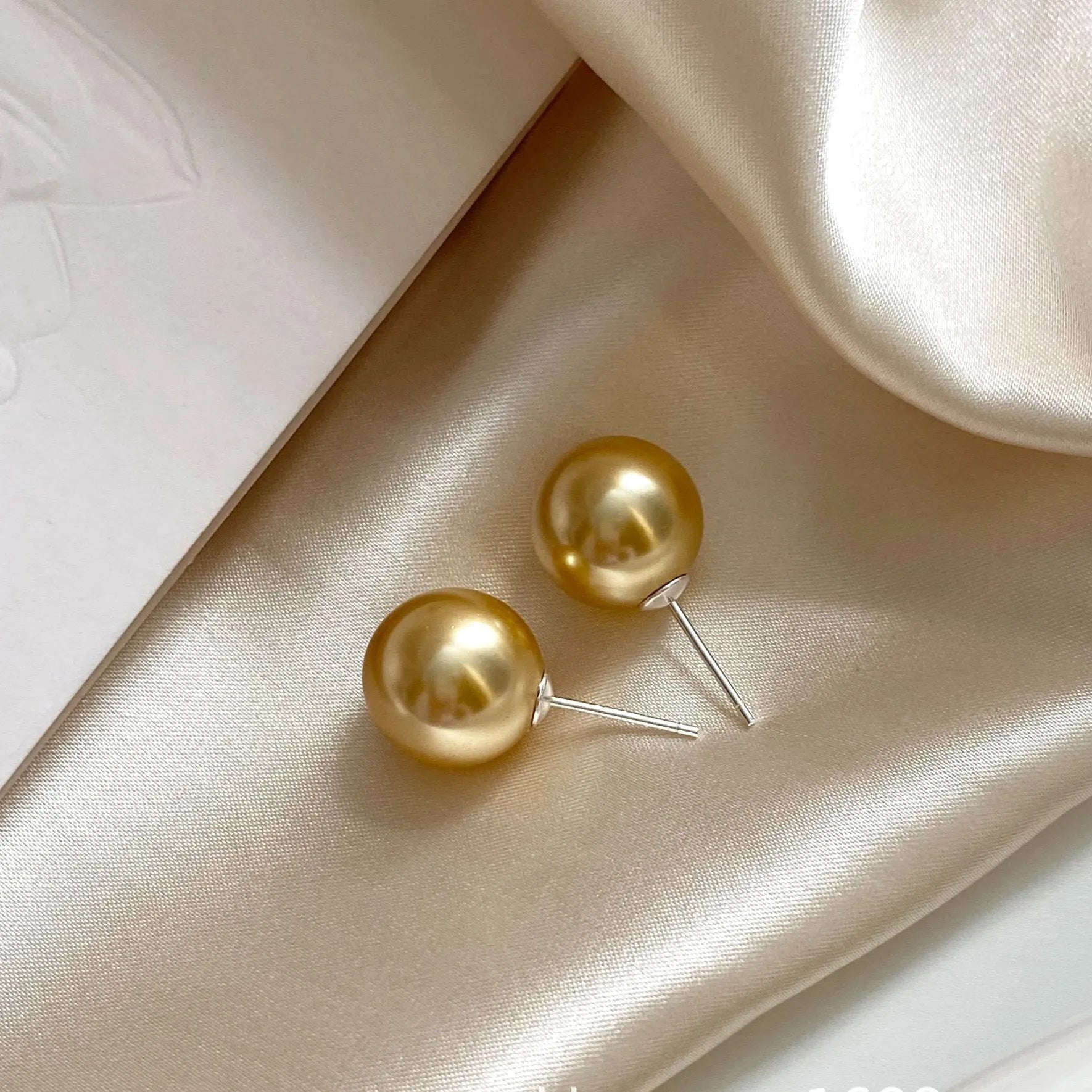 A pair of large geometric pearl stud earrings with an eight-point star accent on a silver setting.