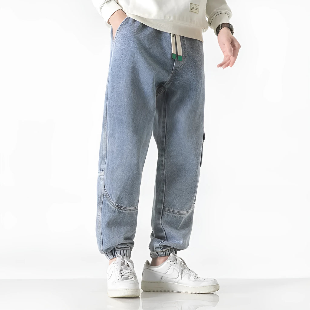 Men's loose-fit tapered cotton trousers in grey, showing the mid-waist and tapered leg cut.