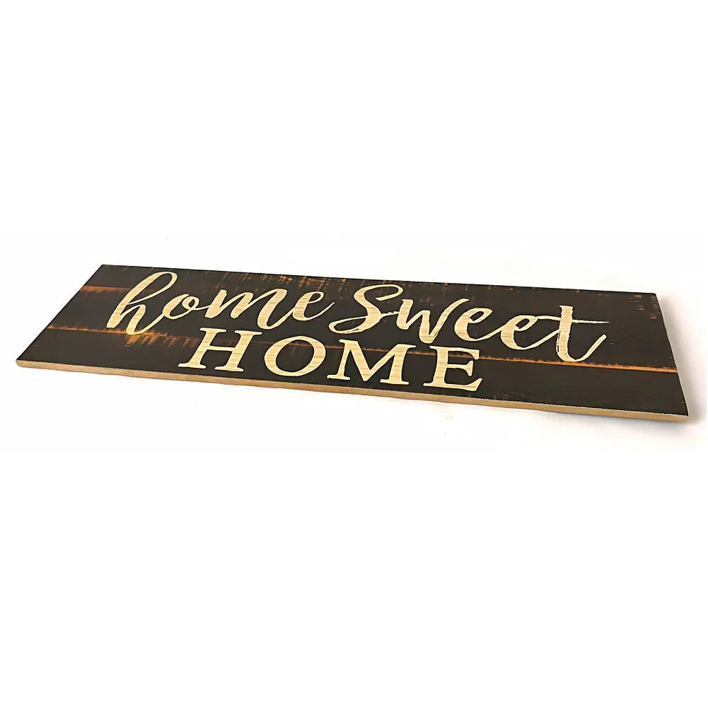 Wooden carved Home Sweet Home wall hanging ornament in black, 40cm long, 12cm high, on a white wall