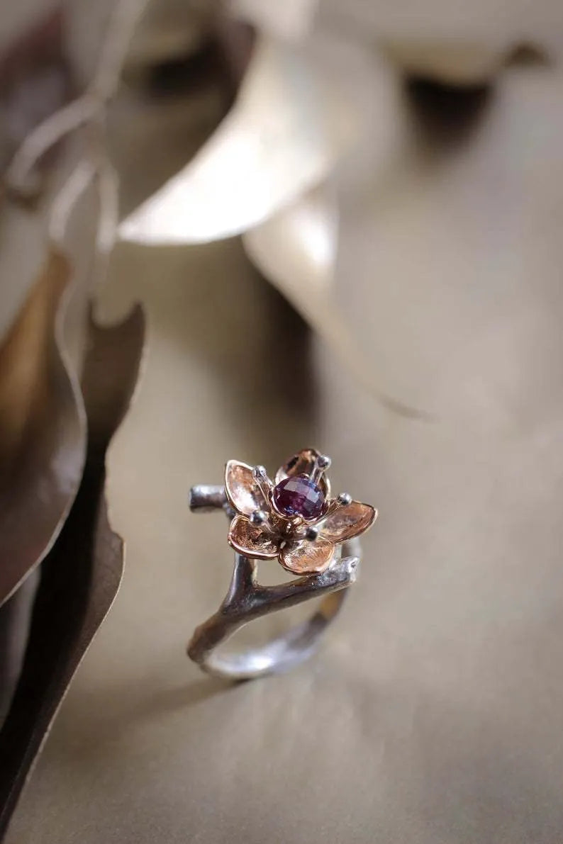 Silver two-tone women's ring with a geometric shape and floral design on a grey background
