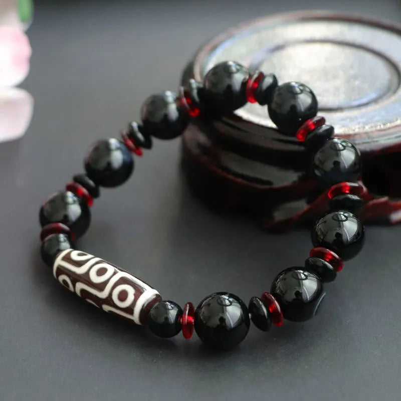 Hand-woven black agate Dzi bead bracelet on a wrist, showing geometric bead and woven band.