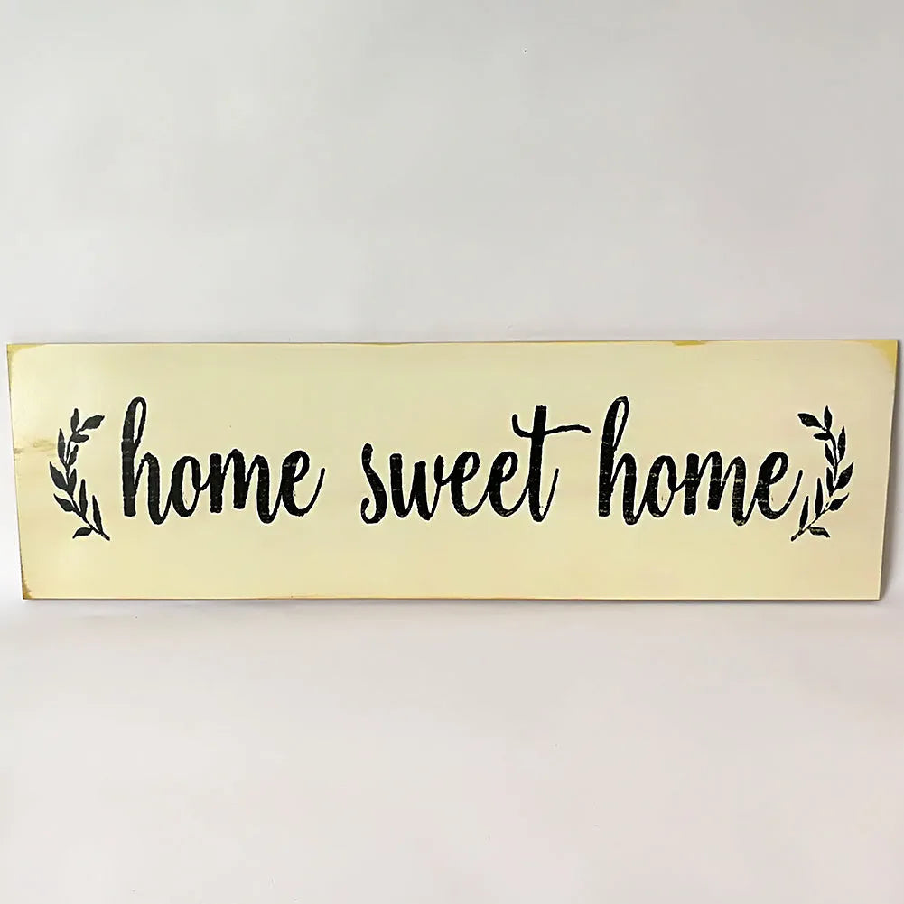 Wooden carved Home Sweet Home wall hanging ornament in black, 40cm long, 12cm high, on a white wall