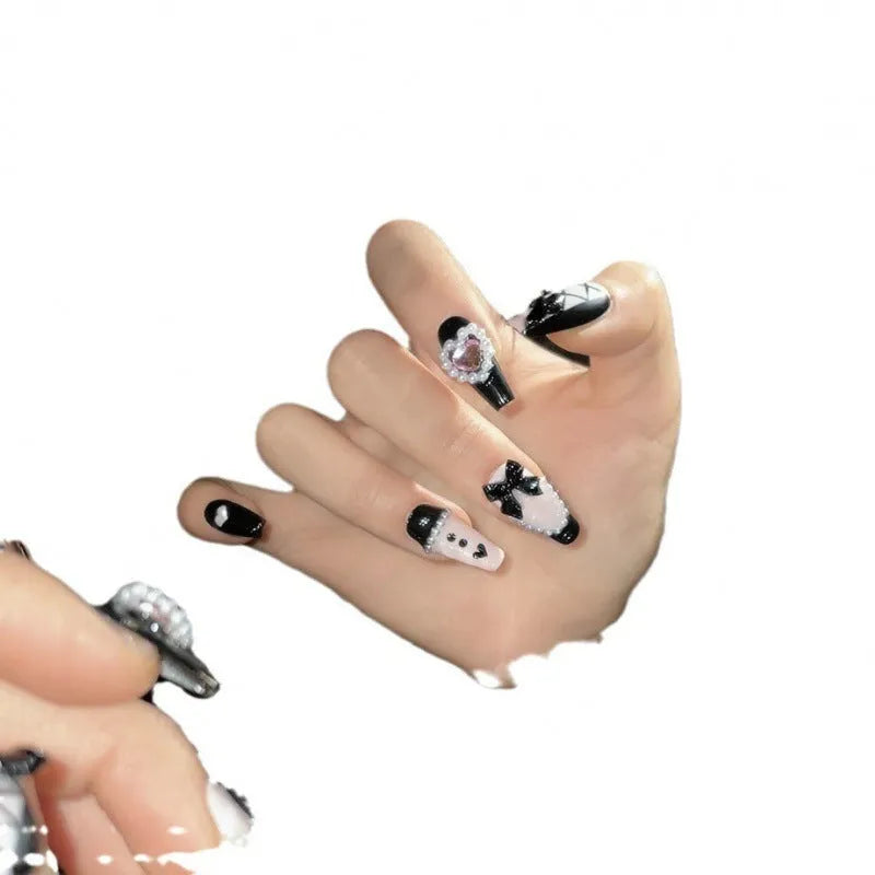 Black and pink heart-shaped handmade manicure set with bow pattern, shown in detachable plastic armour suit.