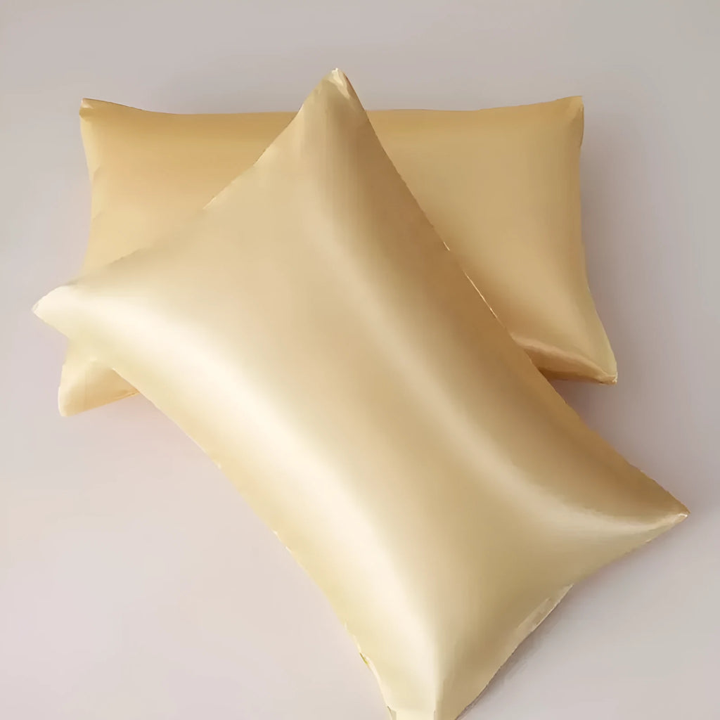 A pair of solid colour satin cloth pillowcases in wine red, shown folded to display their size and smooth texture.