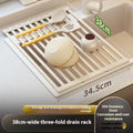 Foldable milky white stainless steel kitchen draining rack next to a sink.