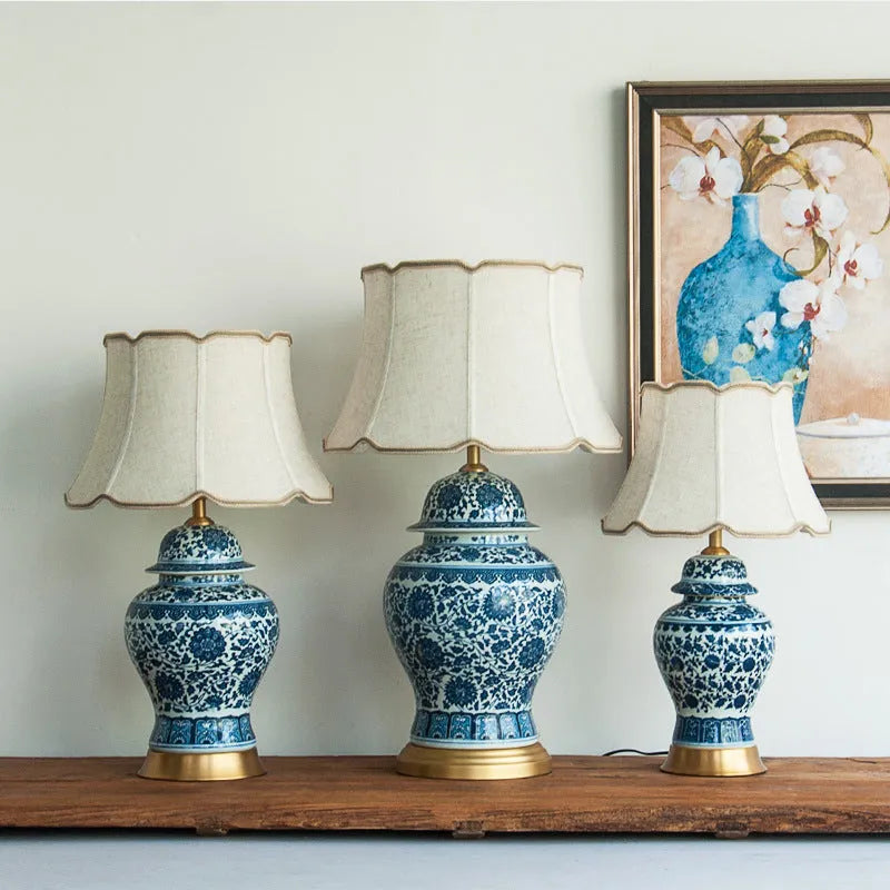 Blue and white porcelain Chinese table lamp with copper base and cloth shade on bedside table