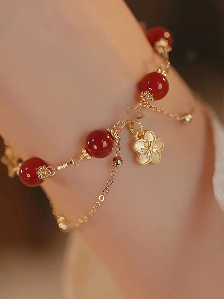 Red agate double layer bracelet with peach blossom charm on an adjustable elastic cord.
