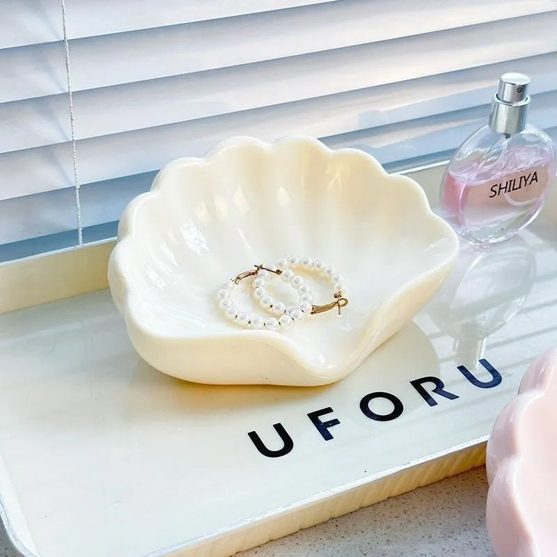 White plastic shell-shaped soap dish with a raised centre, placed on a bathroom counter.