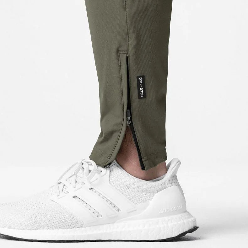 Man wearing dark grey quick-dry fitness trousers with ankle ties, suitable for running and gym workouts.