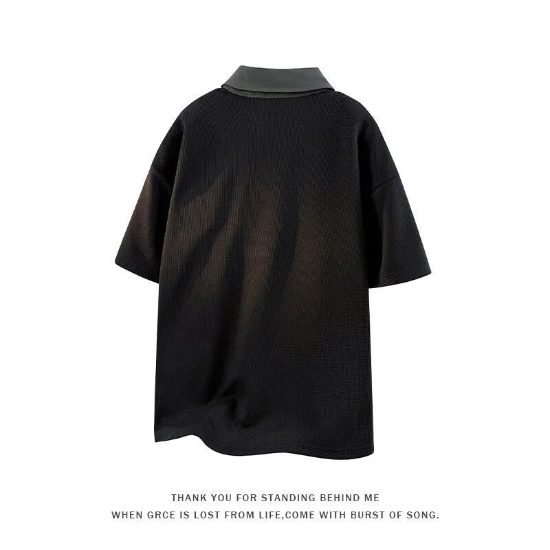 Man wearing a black heavy Henry collar polo shirt sweater with padded shoulders and short sleeves.
