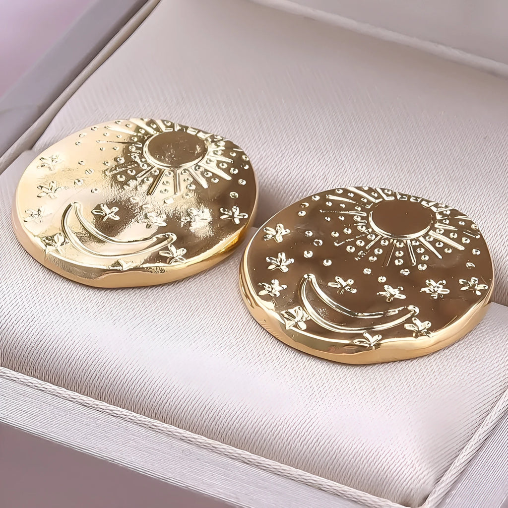 A pair of geometric stainless steel earrings with a small shell detail, shown in gold and silver finish options.