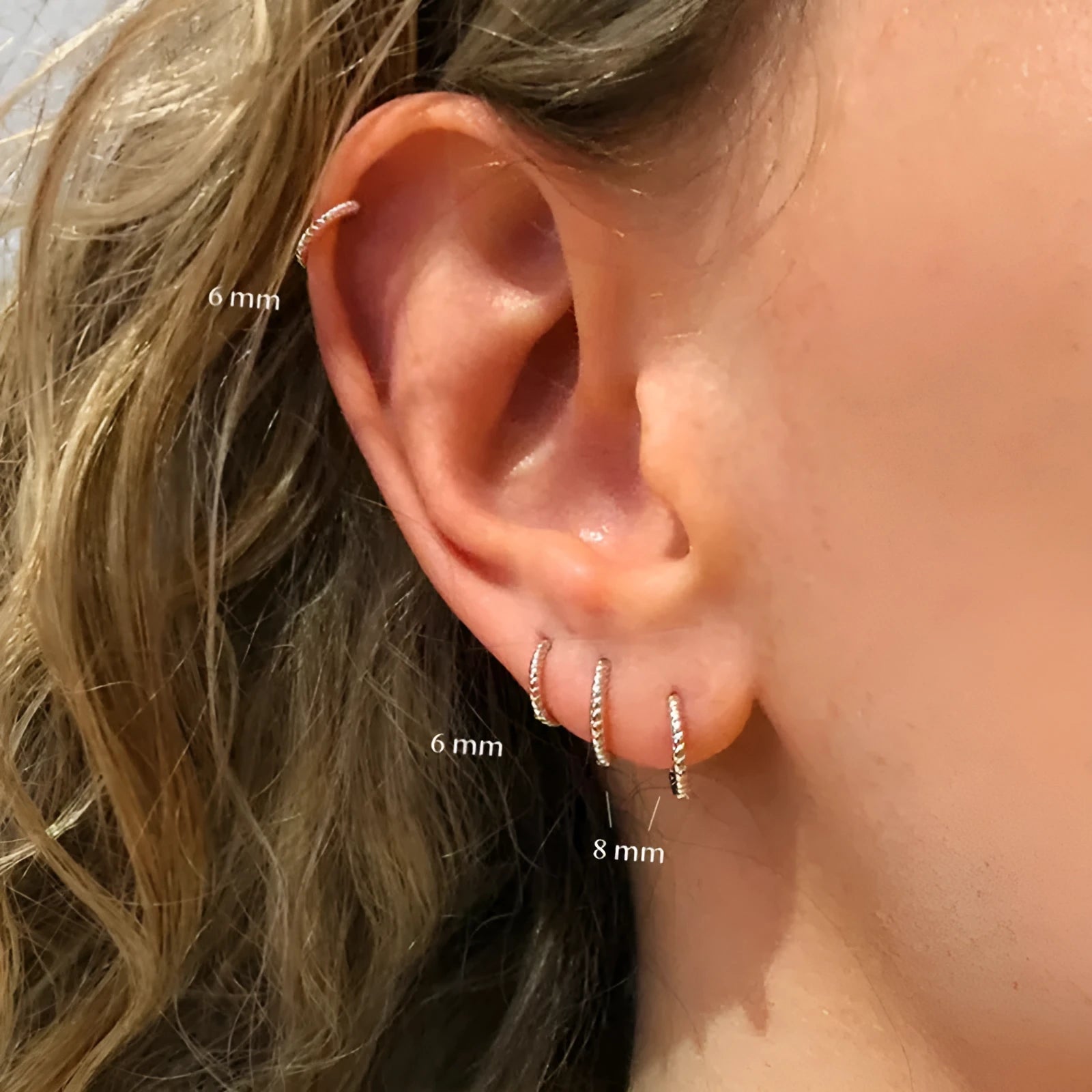 Close-up of a pair of twisted string round sterling silver earrings with gold plating.