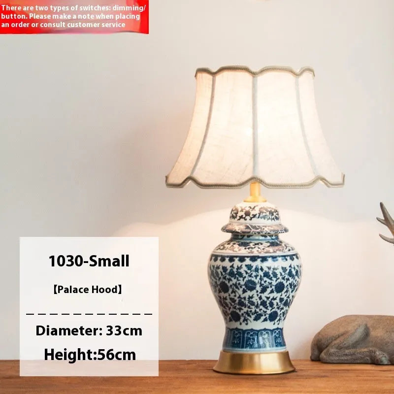 Blue and white porcelain Chinese table lamp with copper base and cloth shade on bedside table