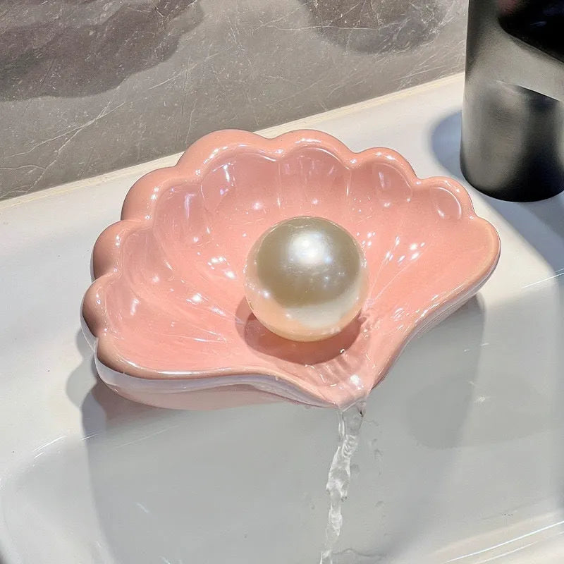White plastic shell-shaped soap dish with a raised centre, placed on a bathroom counter.